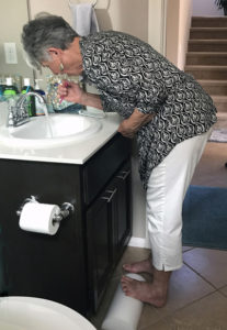 Joyce brushing her teeth while doing calf stretch on half cylinder